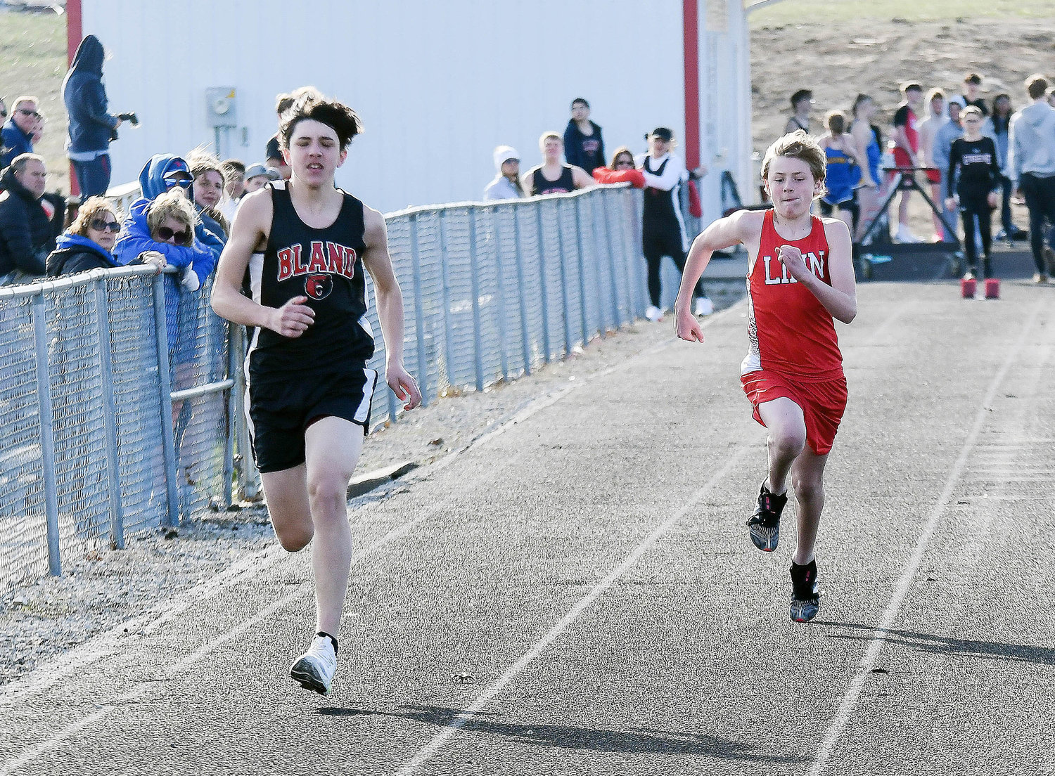Brice Robertson (left) sprints down the track for Bland’s Bears in the 100-meter dash during a season-opening quad track meet Monday at Linn High School.